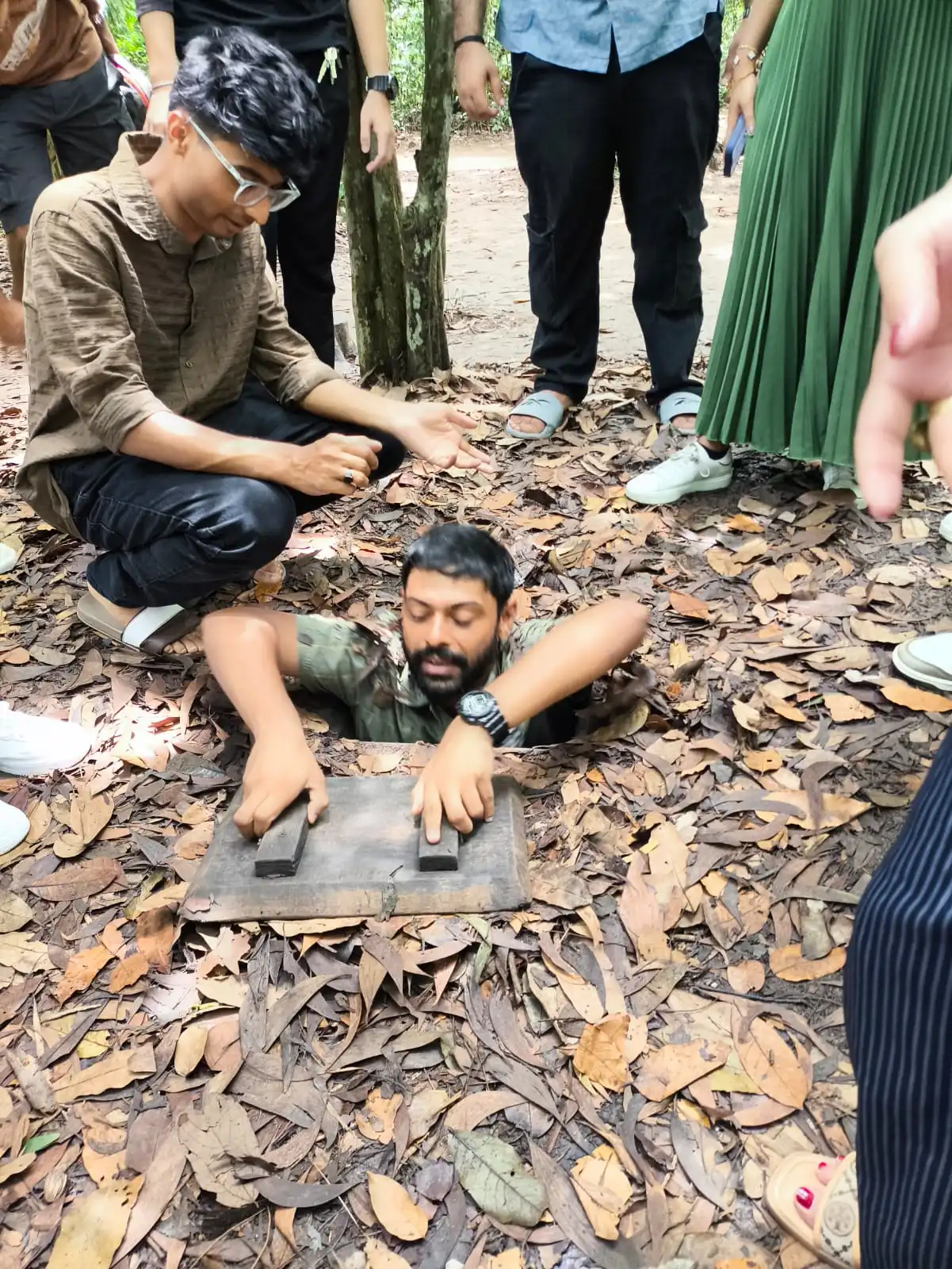 Aniketh climbing through a concealed entrance at the Cu Chi Tunnels